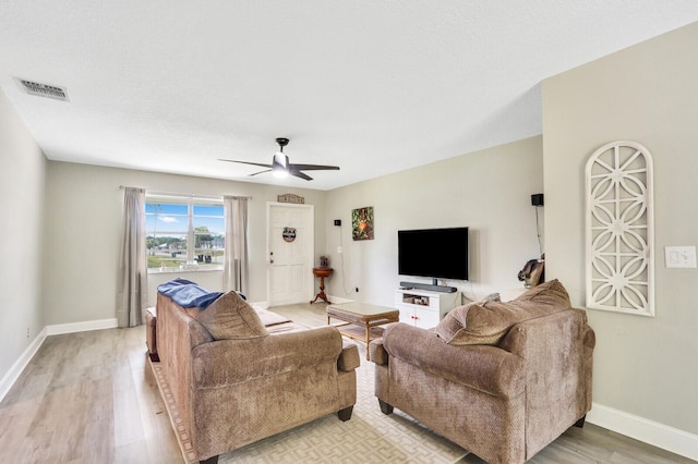 living room featuring visible vents, baseboards, ceiling fan, and light wood finished floors