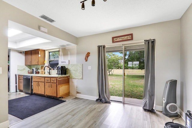 kitchen featuring visible vents, light wood-style floors, light countertops, decorative backsplash, and dishwasher