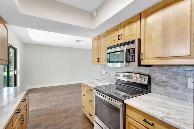 kitchen featuring baseboards, light brown cabinetry, decorative backsplash, appliances with stainless steel finishes, and dark wood-style flooring