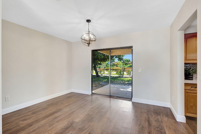 empty room with a notable chandelier, baseboards, and dark wood-style flooring