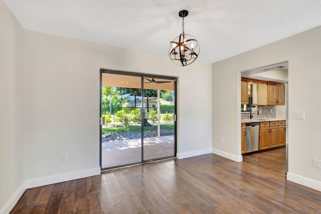 unfurnished dining area with a sink, baseboards, dark wood-type flooring, and an inviting chandelier