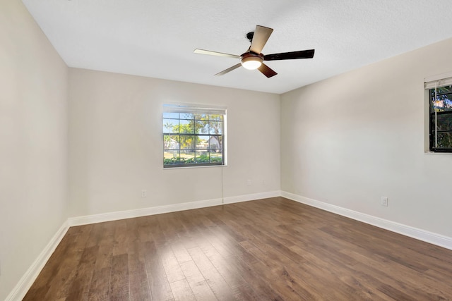 unfurnished room featuring baseboards, dark wood-style flooring, and ceiling fan