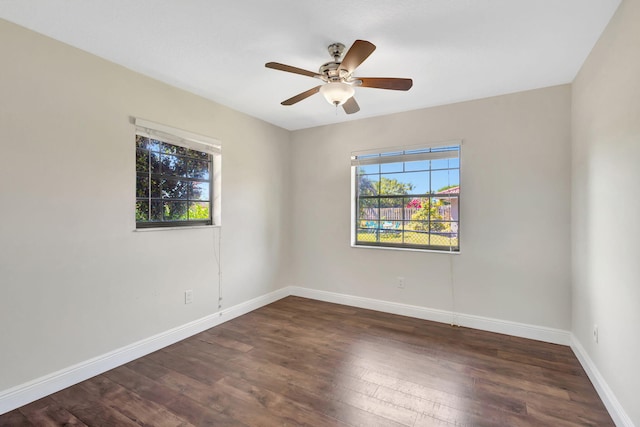 empty room with a wealth of natural light, baseboards, wood finished floors, and a ceiling fan