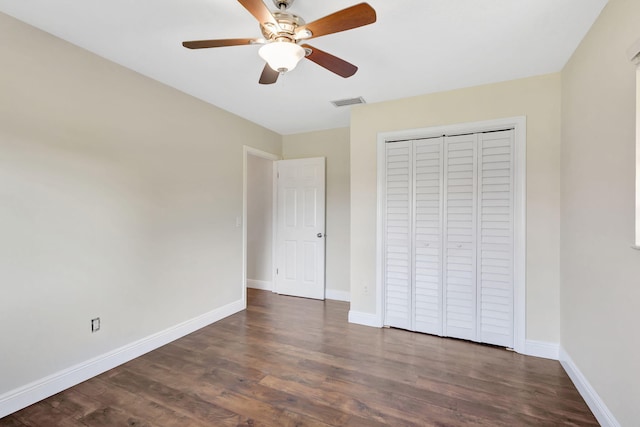 unfurnished bedroom with a closet, visible vents, dark wood-type flooring, and baseboards