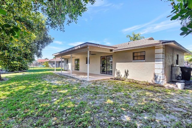 rear view of property with a patio, a ceiling fan, a yard, a fenced backyard, and stucco siding