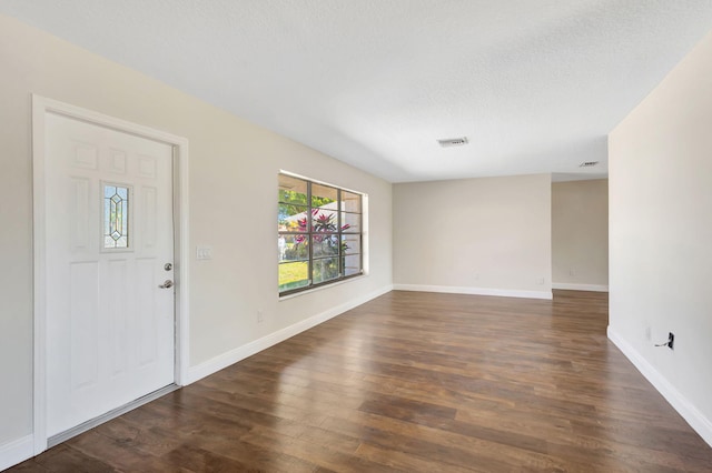 foyer entrance with dark wood finished floors, baseboards, and visible vents