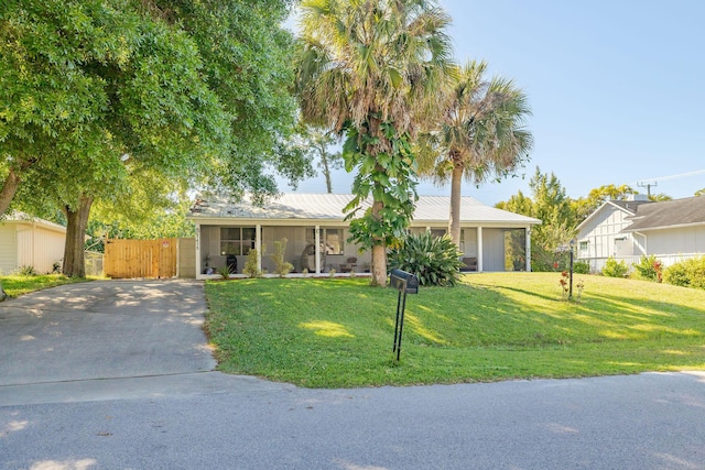 ranch-style house featuring a front yard, fence, driveway, and metal roof