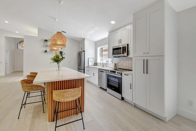 11287 Vivero Ave, Boynton Beach, FL 33437 - kitchen featuring a sink, light wood-style floors, stainless steel appliances, backsplash, and a breakfast bar area