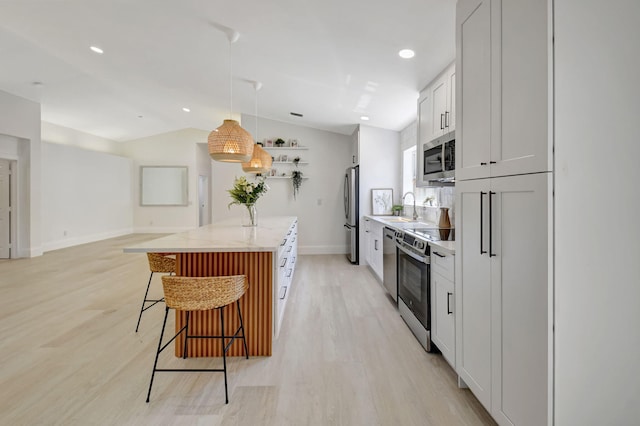 11287 Vivero Ave, Boynton Beach, FL 33437 - kitchen featuring a kitchen breakfast bar, light wood-style flooring, a kitchen island, a sink, and stainless steel appliances