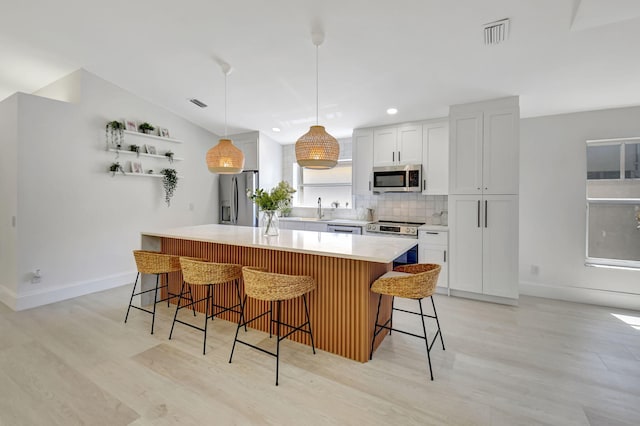 11287 Vivero Ave, Boynton Beach, FL 33437 - kitchen featuring visible vents, appliances with stainless steel finishes, light countertops, a breakfast bar area, and backsplash