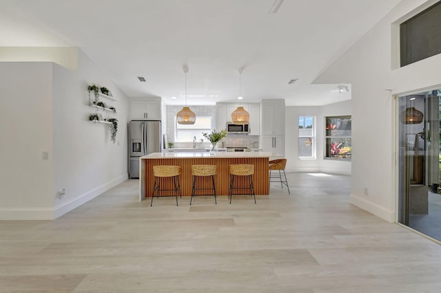 11287 Vivero Ave, Boynton Beach, FL 33437 - kitchen with light countertops, a healthy amount of sunlight, a breakfast bar, and stainless steel appliances