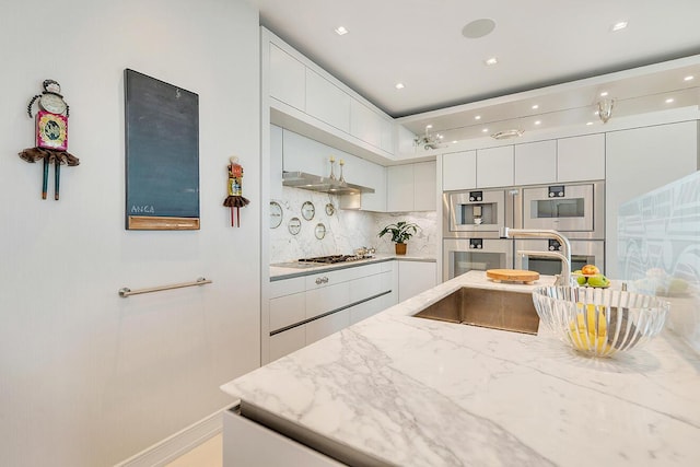 kitchen with modern cabinets, a sink, white cabinetry, stainless steel appliances, and decorative backsplash