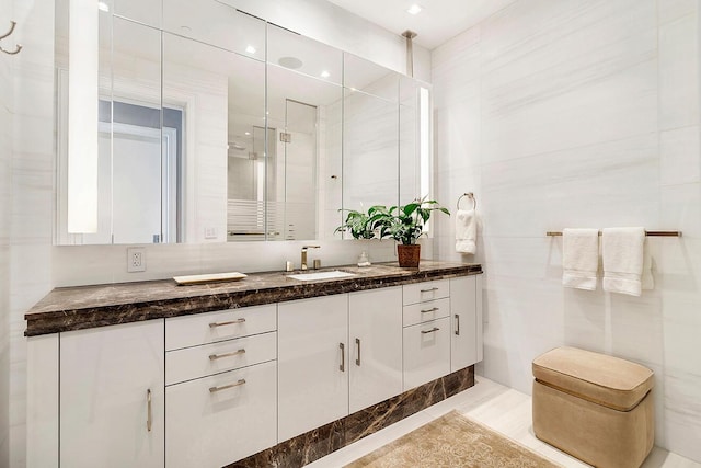 bathroom featuring an enclosed shower, tile walls, and vanity