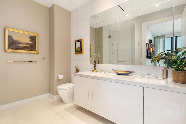 full bathroom featuring baseboards, double vanity, a stall shower, a sink, and toilet