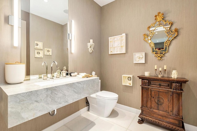 half bathroom with a sink, baseboards, toilet, and tile patterned flooring