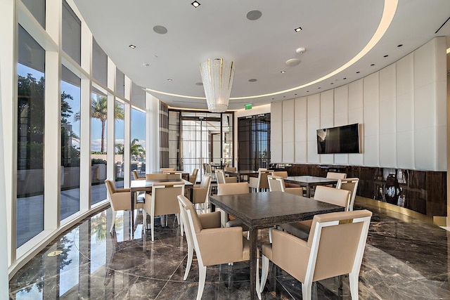 dining area with a wall of windows, recessed lighting, marble finish floor, and a tray ceiling