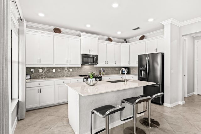 kitchen with a breakfast bar, a sink, decorative backsplash, black fridge with ice dispenser, and white cabinetry