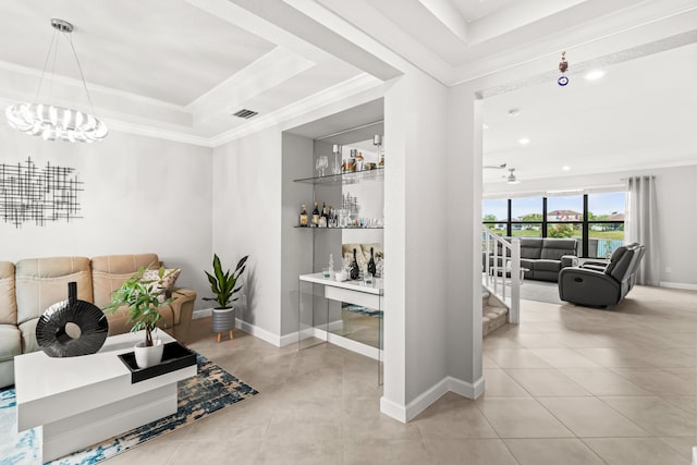 interior space with visible vents, a raised ceiling, crown molding, and built in features