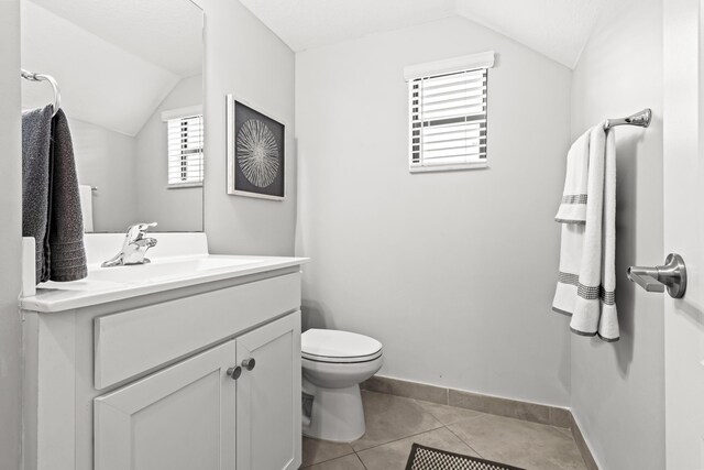 bathroom with vanity, toilet, tile patterned flooring, and vaulted ceiling