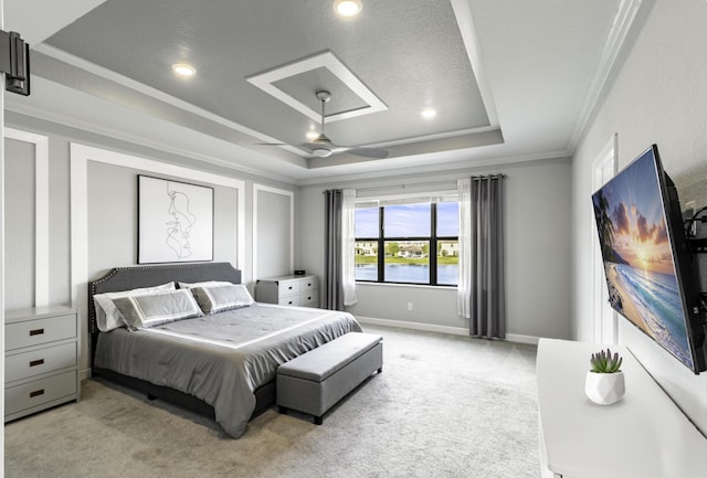 bedroom featuring light carpet, a raised ceiling, ornamental molding, a ceiling fan, and baseboards