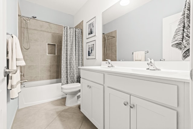 bathroom featuring tile patterned floors, toilet, double vanity, and a sink