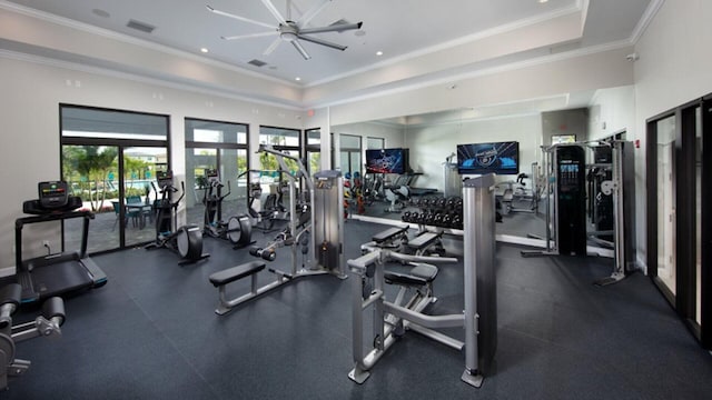 exercise room with visible vents, a raised ceiling, a ceiling fan, and ornamental molding