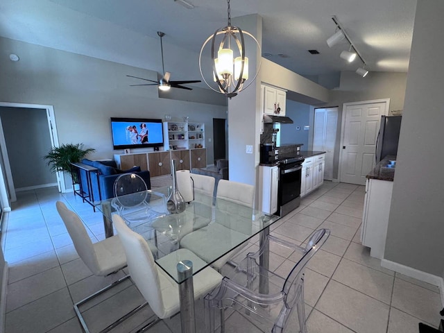 dining space featuring light tile patterned floors, baseboards, lofted ceiling, rail lighting, and ceiling fan with notable chandelier