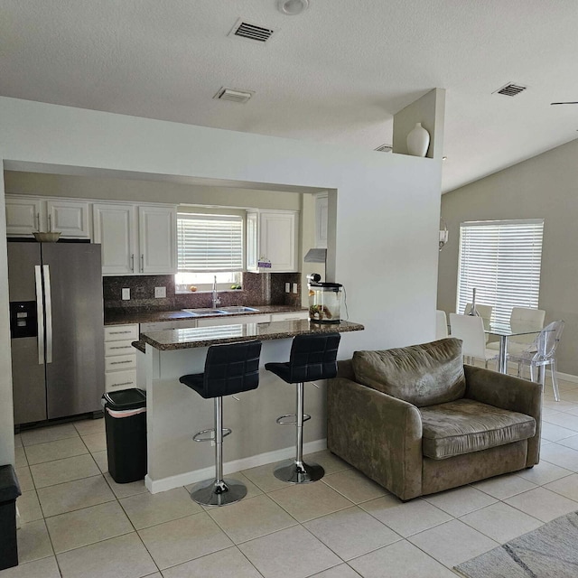 kitchen with visible vents, stainless steel fridge with ice dispenser, a breakfast bar area, white cabinets, and a sink