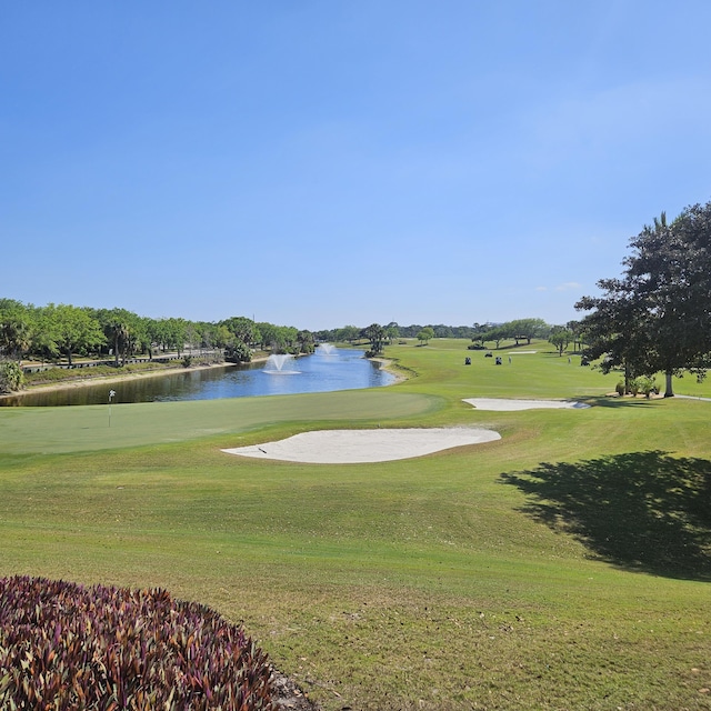 surrounding community featuring a water view, a lawn, and view of golf course