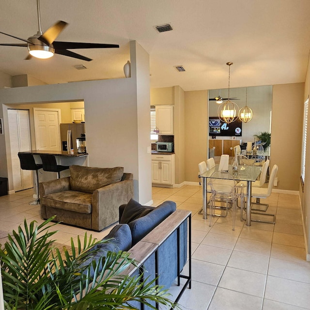 living area featuring visible vents, light tile patterned flooring, and ceiling fan with notable chandelier