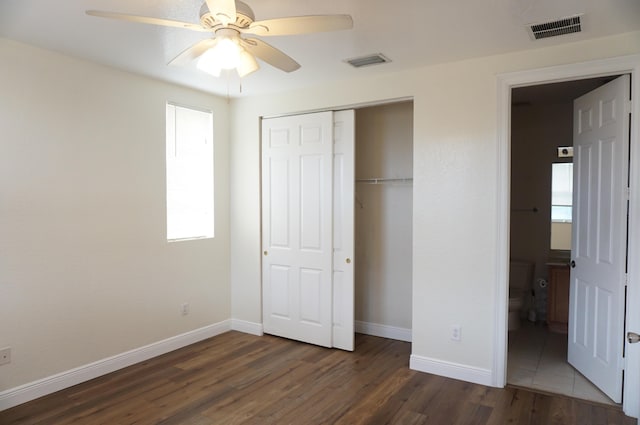 unfurnished bedroom with a closet, visible vents, baseboards, and wood finished floors