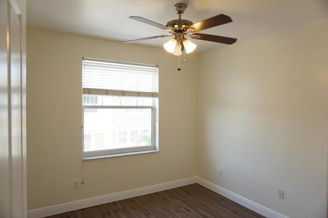 empty room with dark wood finished floors, baseboards, and ceiling fan