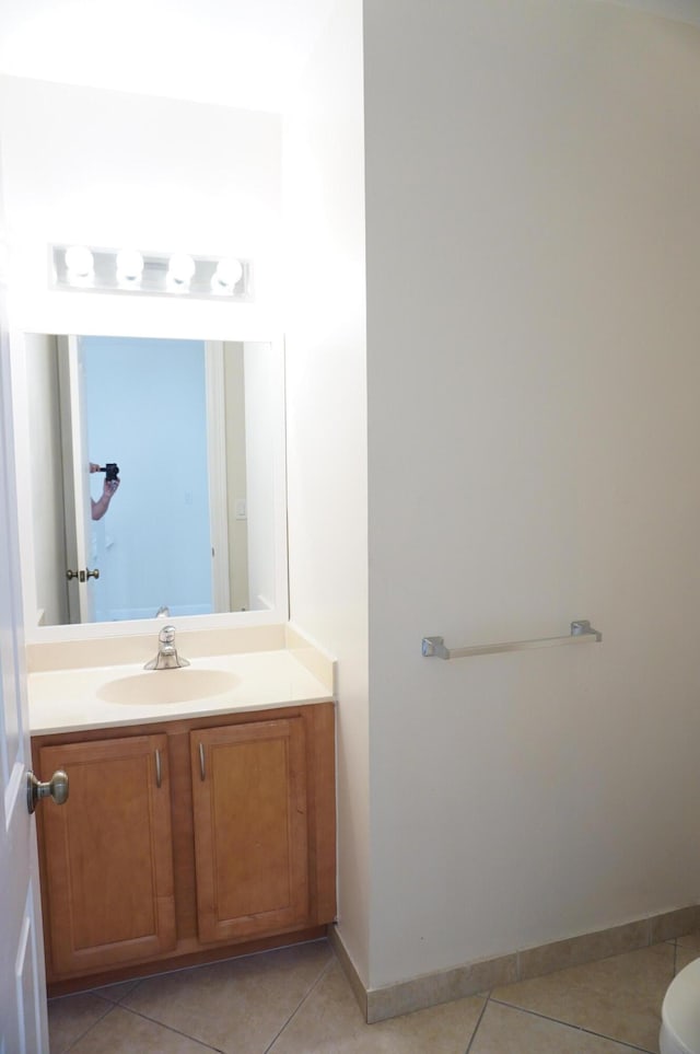 half bathroom with tile patterned floors, toilet, vanity, and baseboards