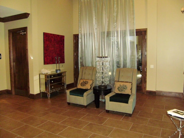 living area with tile patterned floors, baseboards, and a high ceiling