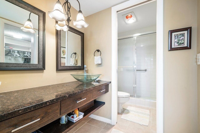 bathroom with toilet, a shower stall, tile patterned flooring, baseboards, and vanity