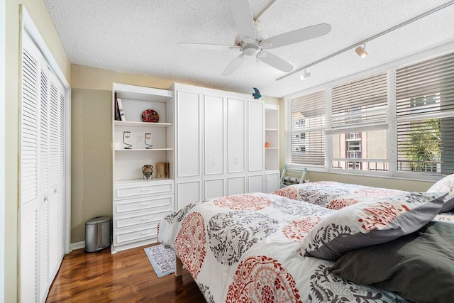 bedroom featuring dark wood finished floors, a ceiling fan, multiple closets, and a textured ceiling