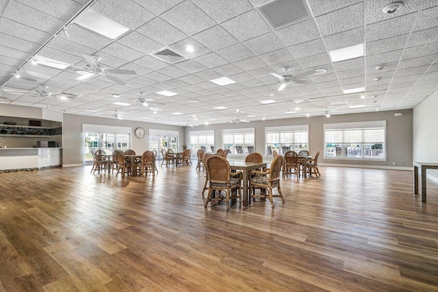 unfurnished dining area featuring wood finished floors, a ceiling fan, and visible vents