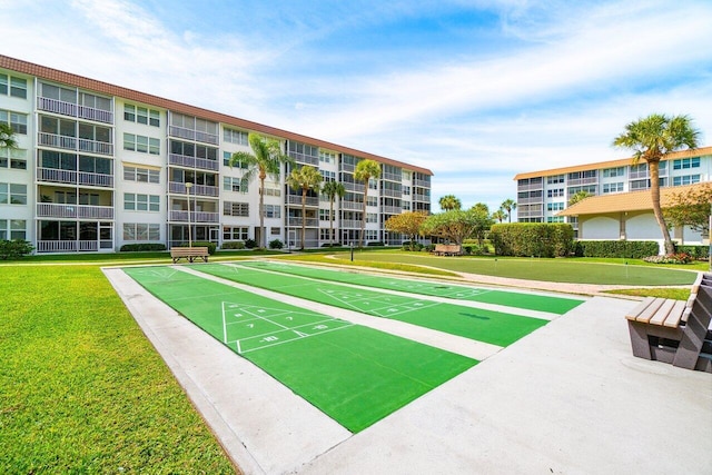 view of home's community with shuffleboard and a yard