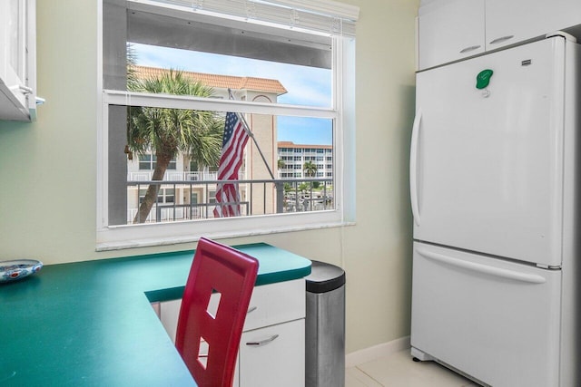 interior space featuring white cabinetry, baseboards, and freestanding refrigerator