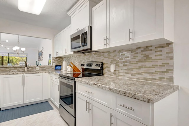 kitchen with backsplash, appliances with stainless steel finishes, and white cabinets