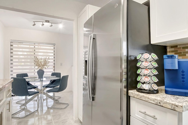 kitchen featuring light stone counters, tasteful backsplash, stainless steel fridge with ice dispenser, and white cabinetry