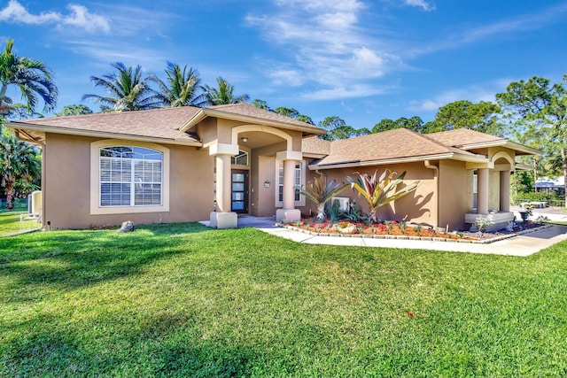 mediterranean / spanish-style home with stucco siding, a front lawn, and roof with shingles