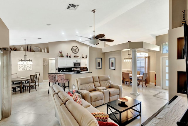 living area featuring visible vents, light tile patterned floors, ceiling fan with notable chandelier, high vaulted ceiling, and ornate columns