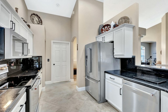 kitchen featuring decorative backsplash, arched walkways, appliances with stainless steel finishes, and white cabinetry