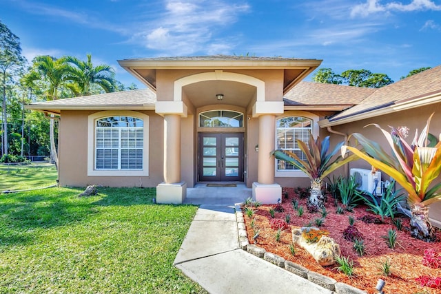 view of exterior entry featuring a shingled roof, a yard, french doors, and stucco siding