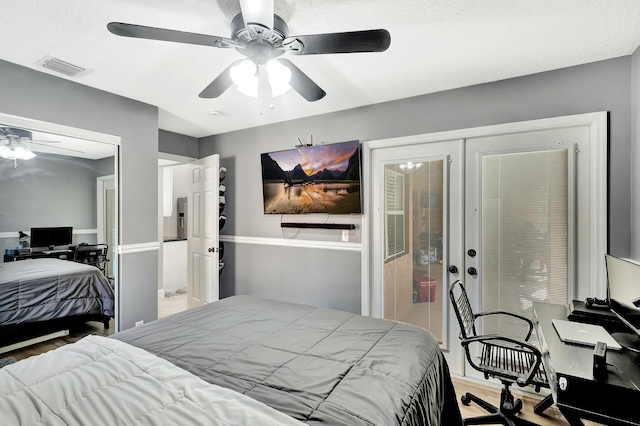 bedroom with wood finished floors, visible vents, and ceiling fan