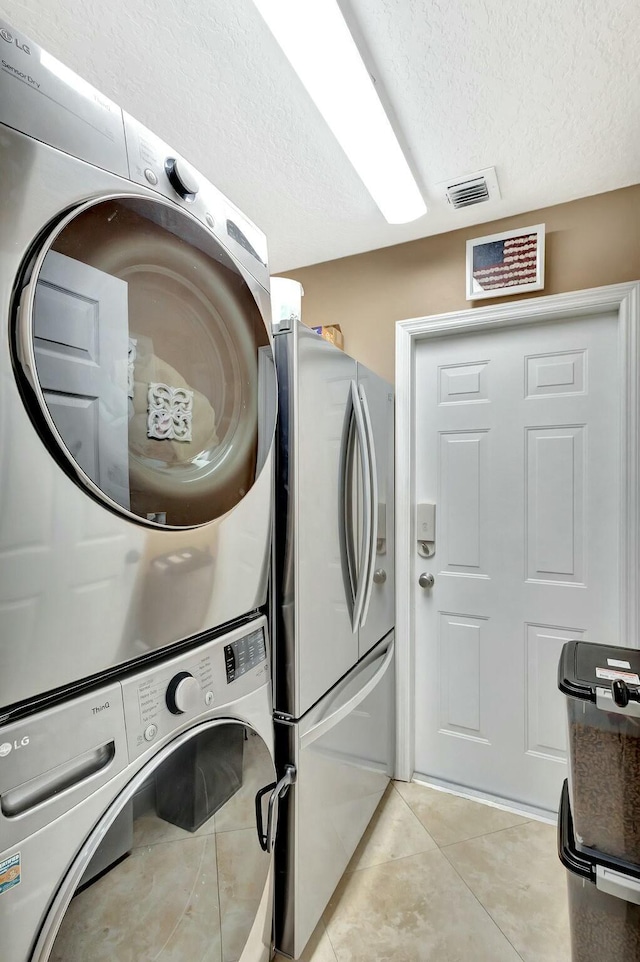 14618 66th St N, Loxahatchee, FL 33470 - washroom with a textured ceiling, light tile patterned flooring, stacked washing maching and dryer, laundry area, and visible vents