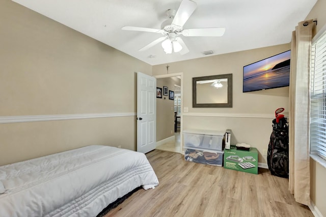 bedroom featuring visible vents, baseboards, wood finished floors, and a ceiling fan