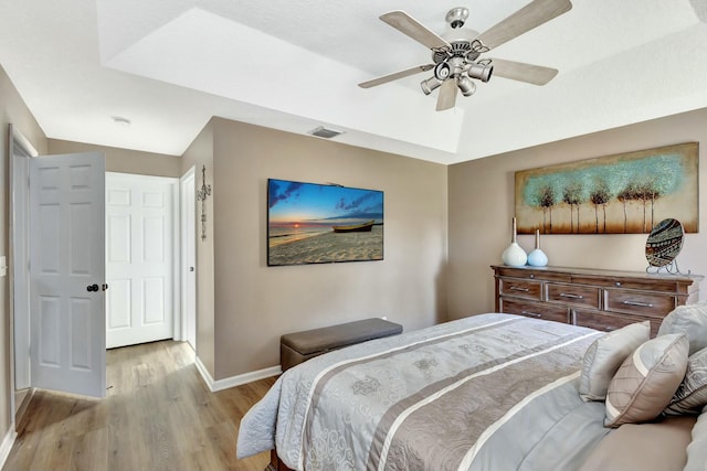 bedroom featuring baseboards, visible vents, light wood-style flooring, ceiling fan, and vaulted ceiling