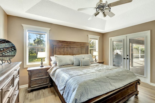 bedroom featuring french doors, multiple windows, light wood-style floors, and access to exterior